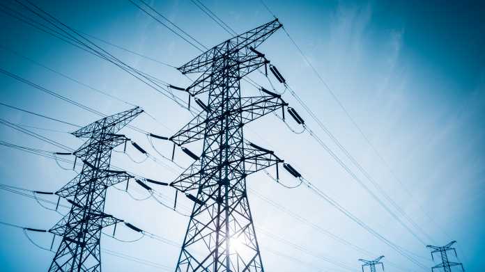 Electricity,Transmission,Pylon,Silhouetted,Against,Blue,Sky,At,Dusk