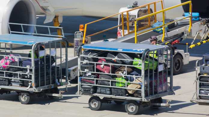 Gepäckwagen voller Koffer vor einer Flugzeugturbine