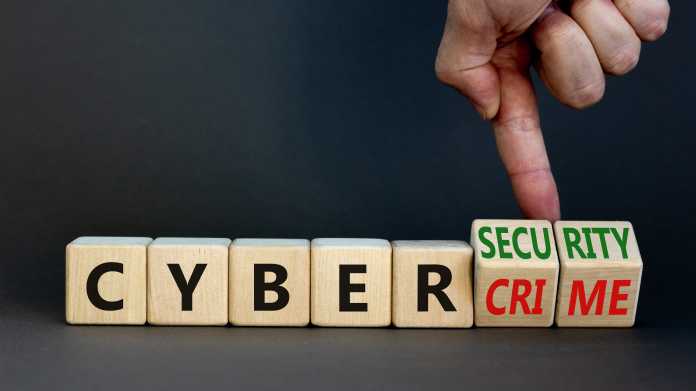Scrabble-Würfel buchstabieren CYBER, gefolgt von zwei Würfeln die gerade von einem Zeigefinger gedreht werden. Sie zeigen sowohl "Crime" als auch "Security"