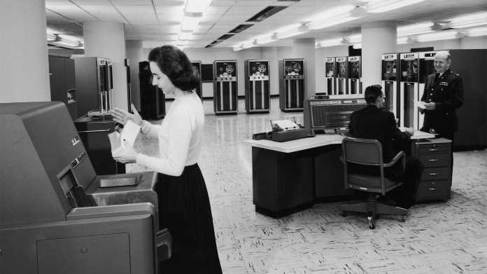 USA 1955: Eine weibliche Angestellte sortiert Lochkarten. An der Konsole des IBM-Großrechners 707 III, der von der US-Armee betrieben wird, sitzt ein Mann., Archive Photos/Getty Images