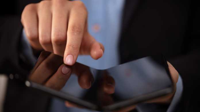 Ein Mann hält einen Finger auf einen faltbaren Bildschirm eines Smartphones oder Tablets.
