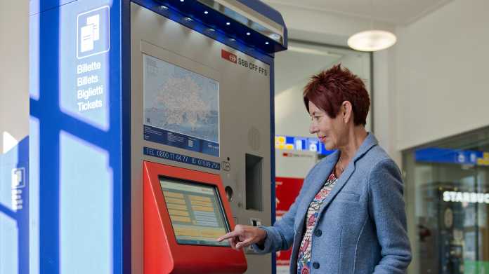 Eine Frau bedient einen Billettautomaten der SBB