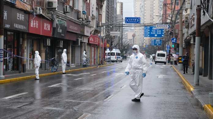 Personen mit weißen Hazmat-Schutzanzügen auf einer leeren Straße in China