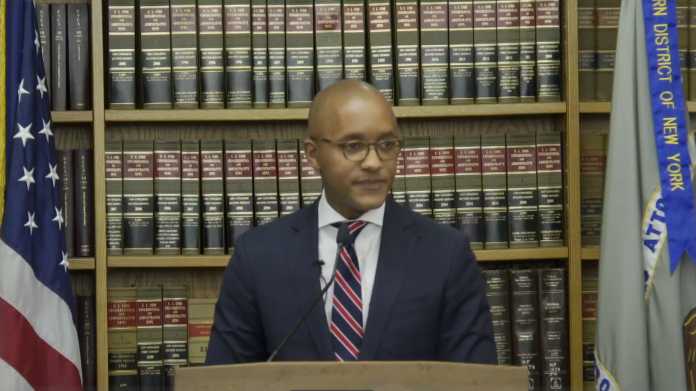 Staatsanwalt Damian Williams an Redenerpult, links eine US-Fahnre, rechts eine Fahne New Yorks