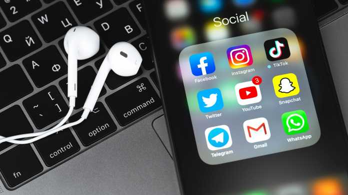iPhone mit zahlreichen Apps auf Laptop neben Kopfhörern