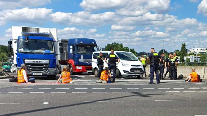 Aktivisten der Bewegung "Letzte Generation" haben sich vor einer Autobahnauffahrt in Berlin auf der Straße festgeklebt und blockieren den Verkehr, die Polizei ist vor Ort.