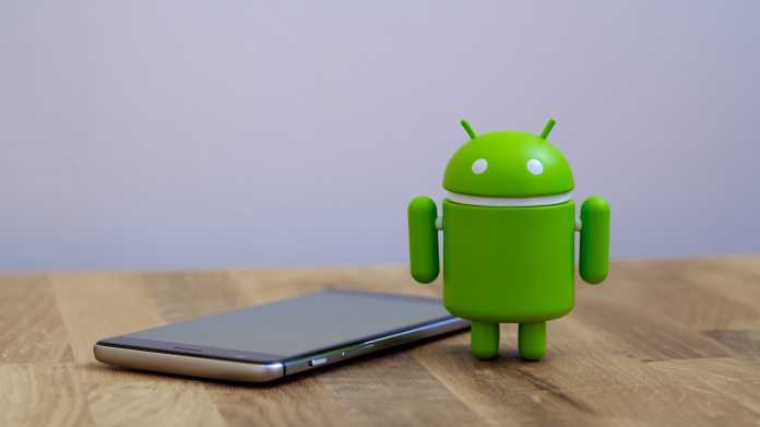 Smartphone neben Googles Android-Figur auf einem Tisch