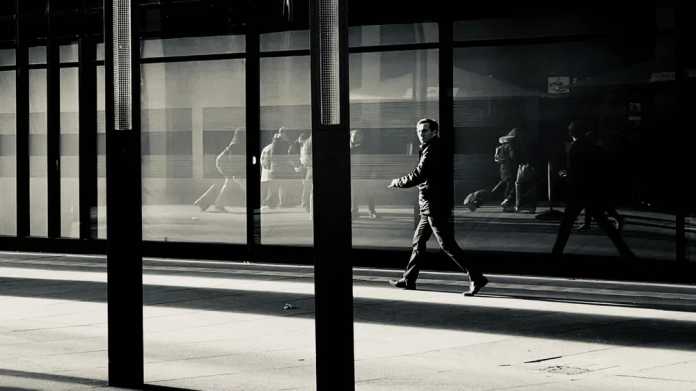 Mann läuft vor Glasfassade in Schwarzweiß