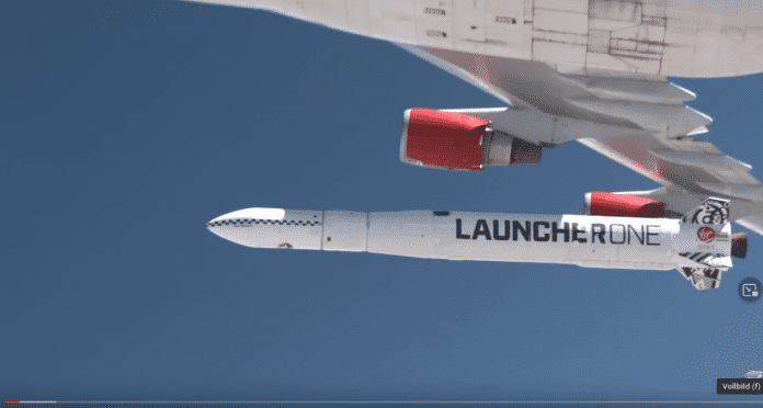 A small rocket labeled LauncherOne directly under an airplane, a fraction of a second after it was released from there