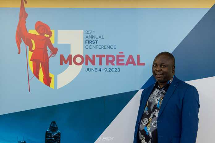 Christopher Banda neben dem Werbesujet der FIRST Conference 2023 in Montreal