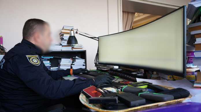 Polizist sitzt an Computer eines Verdächtigen