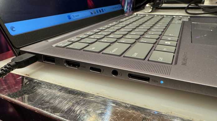 Die Steckdosen und die Tastatur eines aufgeklappten Laptops von der linken Seite gesehen, darunter 