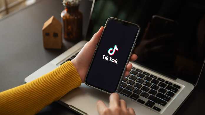 Frau nutzt TikTok auf Smartphone zu Hause