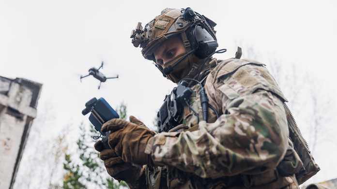 Soldat, der Drohne am Himmel mit Smartphone steuert