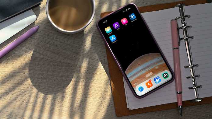 Ein iPhone neben einer Kaffeetasse, auf dem Homescreen sind App-Läden zu sehen