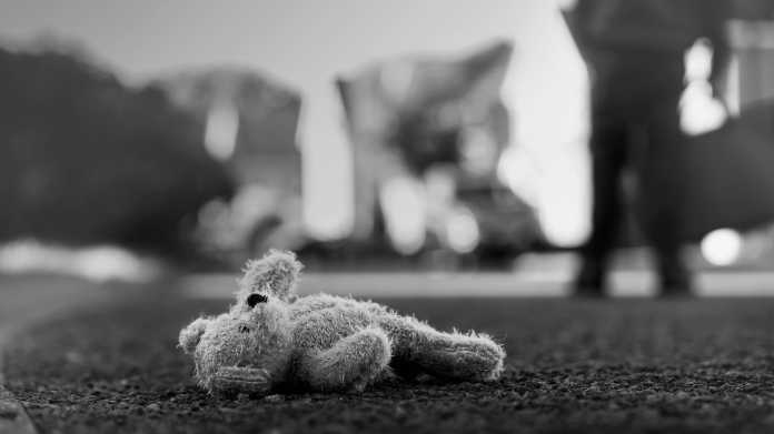 Ein Teddybär liegt auf dem Boden vor verschwommenen Hintergrund in Schwarz-Weiß