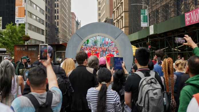 Viele Menschen vor einem runden Objekt mit einem Bildschirm in der Mitte.