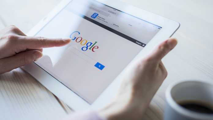 Die Seite von Google auf einem Tablet in den Händen einer Person, die auf das Suchfeld tippt.