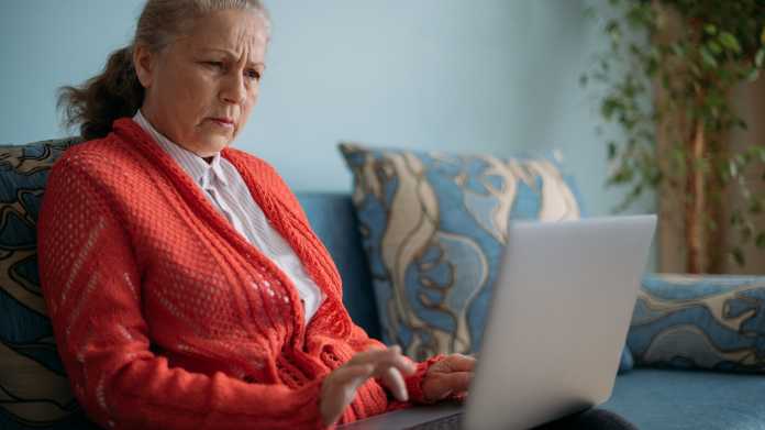 Ärgerliche Seniorin an einem Laptop