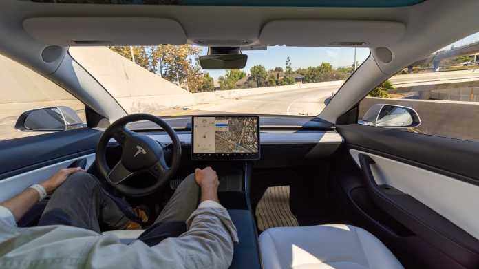 Fahrer eines Tesla ohne Hände am Steuer auf der Straße