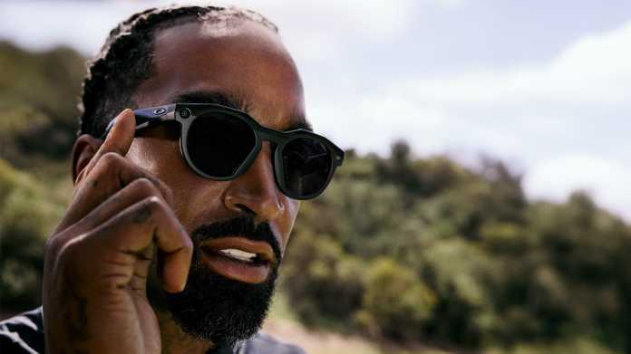 Der Golfspieler JR Smith tippt auf den Bügel seiner dunklen Oakley Meta HSTN, ein Wald im Hintergrund.