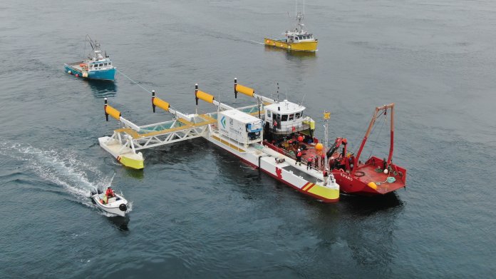 Plattform wird von Schiffen in Stellung gebracht, 4 Turbinen stehen waagrecht zur Wasseroberfläche