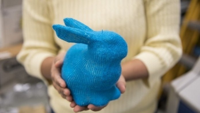 Zwei Hände halten einen blauen Hasen aus Strick