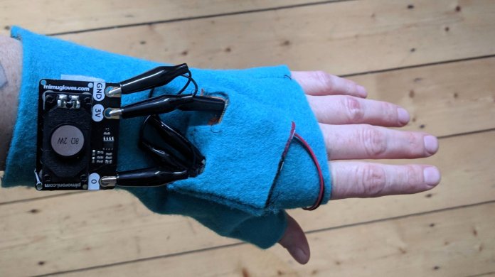 Eine Hand hält einen Handschuh mit aufgenähter Elektronik.