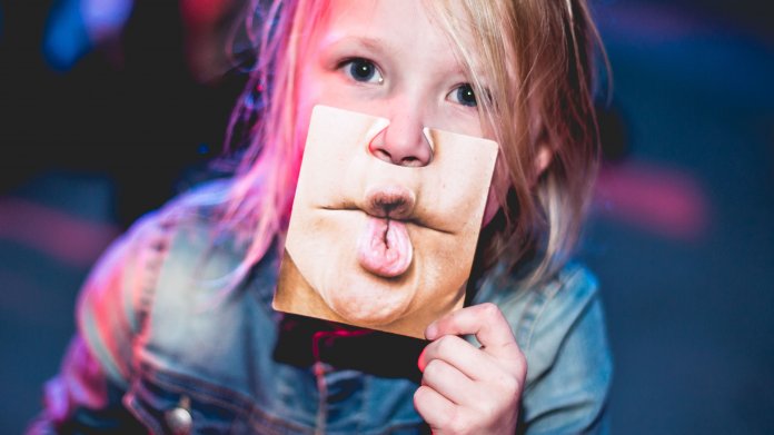 Kind hält sich Foto eines Mundes eines Erwachsenen vor den Mund