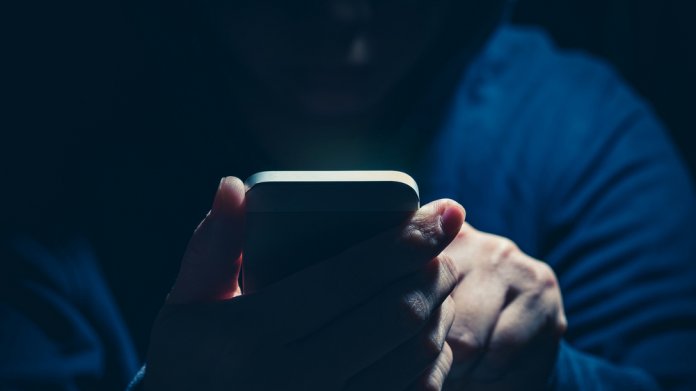 Symbolbild - ein umschatteter User hält ein Handy