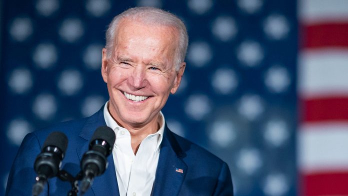 Jo Biden lächelnd vor zwei Mikrofonen