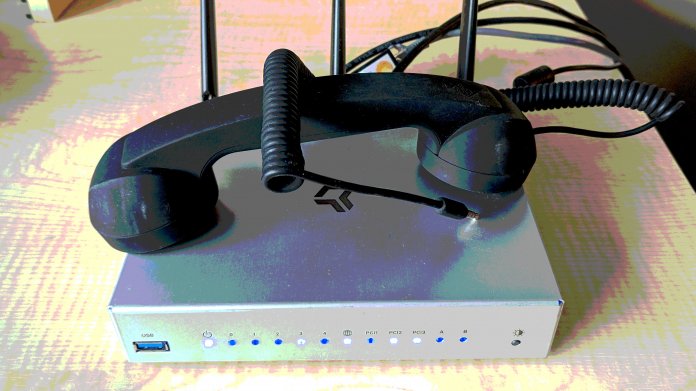 Ein Telefonhörer mit Autostecker liegt auf einem WLAN-Router