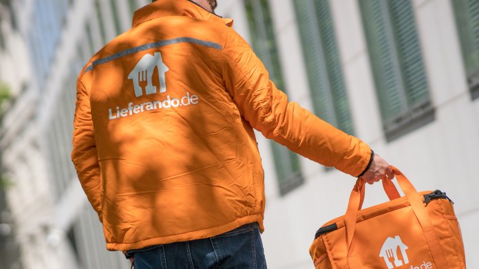 Mann in oranger Uniformjacke trägt eine orange Tasche