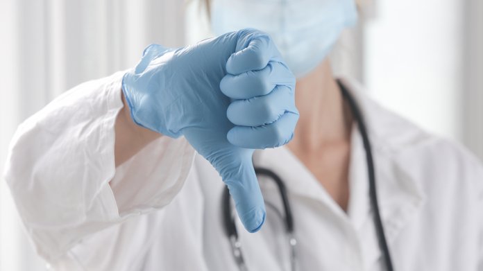 Ärztin zeigt Daumen nach unten