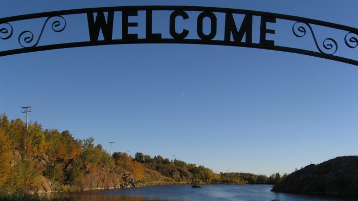 See, herbstliche Bäume, davor ein Bogen mit Aufschrift "WELCOME"