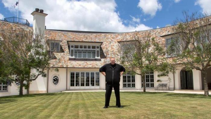 Rasen, Bäume, Haus, davor Kim Dotcom