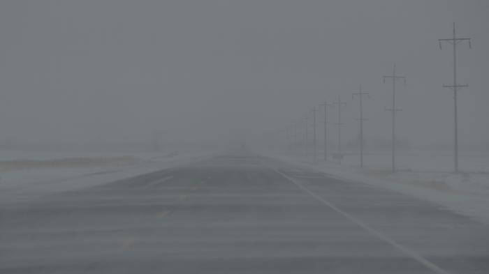 Fahrbahn mit Nebel und Schneeverwehungen