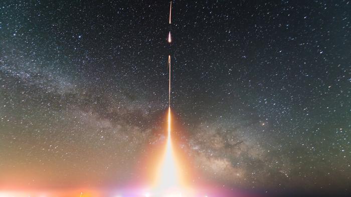 Sternenhimmel, davor Rakete mit Feuerstrahl