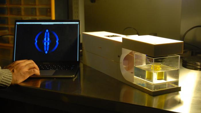 Ein neuartiger 3D-Drucker steht neben einem aufgeklapptem Laptop.