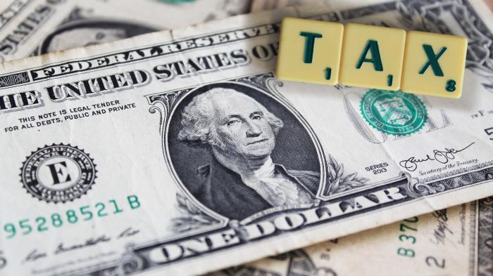US-Dollar-Note, darauf liegen Scrabble-Buchstaben TAX