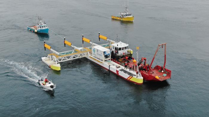 Plattform wird von Schiffen in Stellung gebracht, 4 Turbinen stehen waagrecht zur Wasseroberfläche