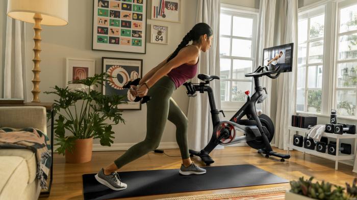 Frau trainiert mit Gewichten, Fitnessbike im Hintergrund