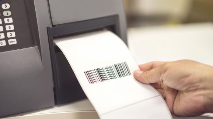 Ein Etikett mit einem Barcode wird aus einem Drucker entnommen.