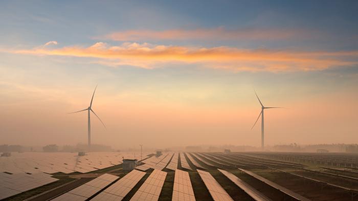 Windkraftanlagen hinter Solarpaneelen in der Landschaft