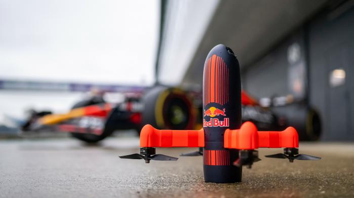 Das Foot zeigt die Kameradrohne von Red BVull vor einem Formel 1 Fahrzeug.