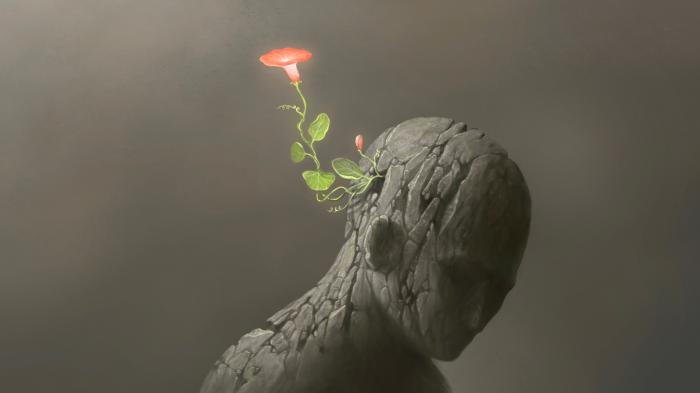Steinfigur aus deren Hinterkopf eine Blume mit rosa Blüte herrauswächst.