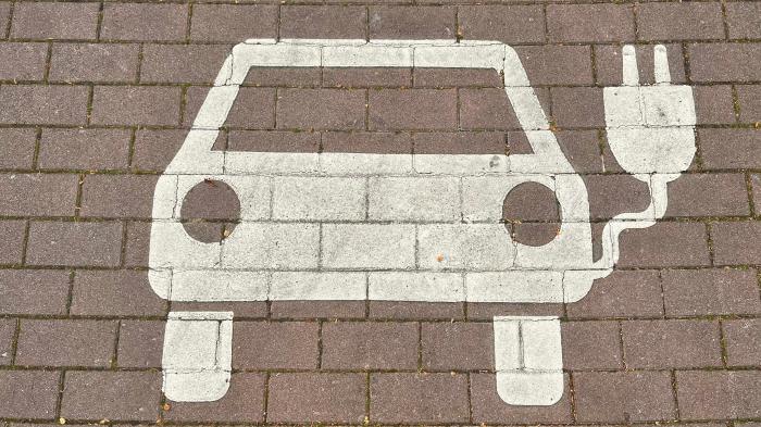 Ein auf Pflastersteinen gemaltes Auto mit Stromstecker