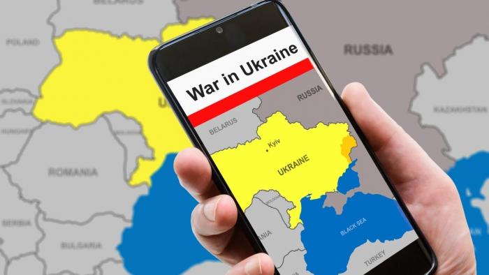 Handy mit Überschrift Krieg in der Ukraine vor der Karte der Ukraine, gezeichnet in Farben der Ukraine