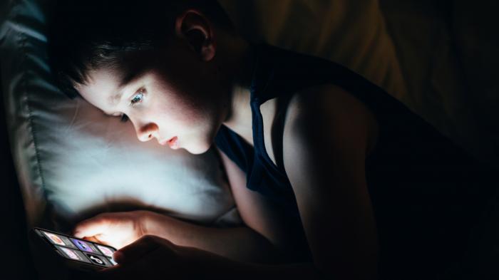 Child looks at an illuminated display in the dark