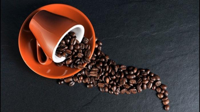 Symbolbild: Umgestürzte Espressotasse mit Kaffeebohnen